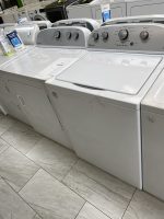 Row of white Whirlpool washing machines in a showroom, with metal control panels and price tag on display gear.