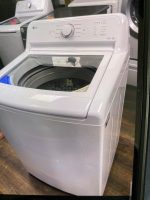 ccd27329-00ea-409d-bd03-81a41e5e1328-18219-000006205e46ef28_file - Discount Appliances White LG top-loading washing machine with its lid open, exposing the drum; a second washer is visible in the background.